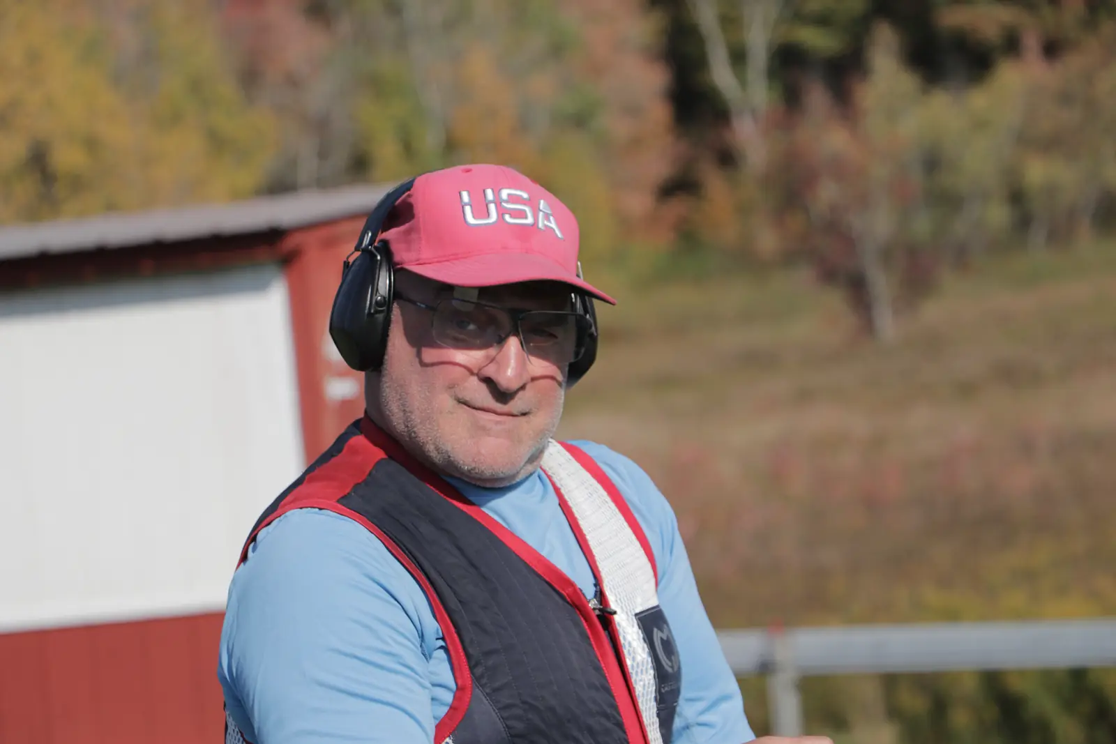 Smiling shooter wearing a USA cap and hearing protection